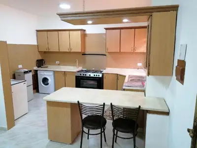 a kitchen with a counter and two chairs in it at EMILE ALTWAL Hotel in Madaba