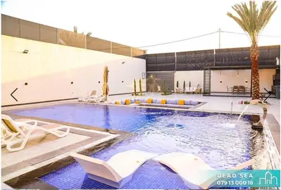 a large swimming pool with chairs and a building at PYRAMID Chalets - شاليهات الهرم in Al Baḩḩāth
