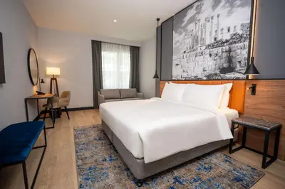 a hotel room with a large white bed and a desk at Radisson Blu Hotel, Amman Galleria Mall in Amman