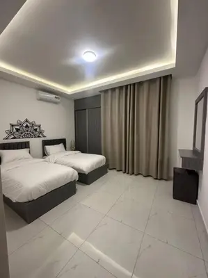 a hotel room with two beds and a television at cozy home near all services (21) in Rujm ash Sharāʼirah