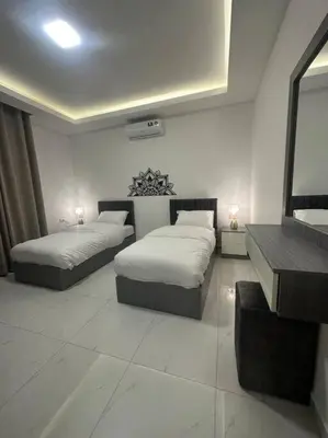 a bedroom with two beds and a table and a mirror at cozy home near all services (22) in Rujm ash Sharāʼirah