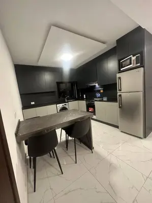 a kitchen with a table and chairs and a refrigerator at cozy rooftop near al services 23 in Rujm ash Sharāʼirah