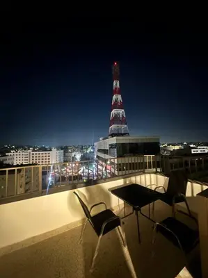 a balcony with two chairs and a table and a tower at cozy rooftop near al services 23 in Rujm ash Sharāʼirah