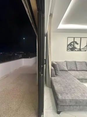 a living room with a couch and a view of the city at cozy rooftop near al services 24 in Rujm ash Sharāʼirah