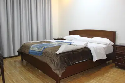 a bedroom with a bed with a wooden headboard and curtains at الأحفاد للشقق الفندقية Al Ahfad Hotel Apartments in Şāfūţ