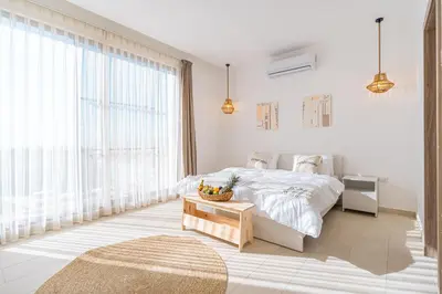 a white bedroom with a bed and a table at Nammos Experience in Amman