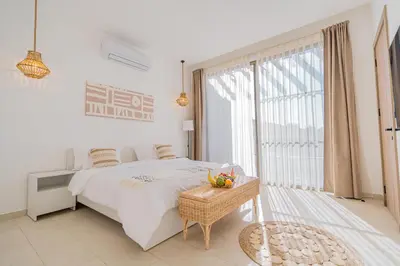 a white bedroom with a bed and a large window at Nammos Experience in Amman
