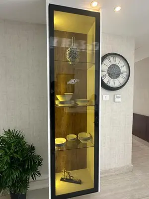 a display case with bowls and a clock on a wall at Abdoun luxurious apartment in Amman