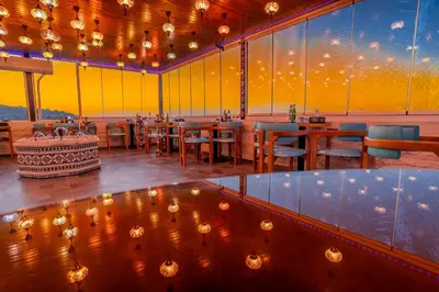 a restaurant with tables and chairs and a yellow wall at Petra Bermudez Hotel in Wadi Musa