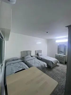 a room with three beds and a table in it at شقه مفروشه مميزه in Irbid