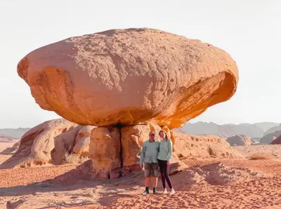 a couple standing in front of a rock formation at Wadi rum camp in Wadi Rum