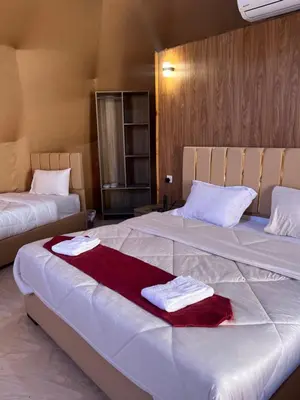 two beds in a hotel room with towels on them at Madonna Rum camp bubbles & Jeep tours in Wadi Rum
