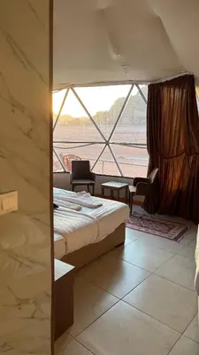 a room with two beds and a large window at Madonna Rum camp bubbles & Jeep tours in Wadi Rum