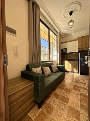 a living room with a green couch and a kitchen at 4/ Antica jabalal-lwebdeh in Amman