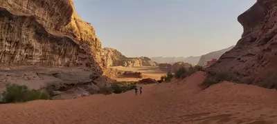 two people walking through the desert in a canyon at Wadi Rum Legacy Camp & Tours in Wadi Rum