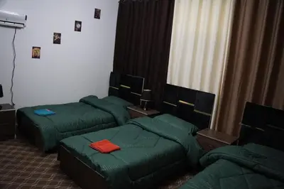 a room with three green beds and a couch at Petra inbox Hostel in Wadi Musa