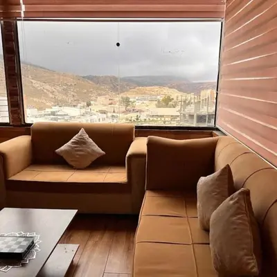 a couch in a room with a large window at Petra inbox Hostel in Wadi Musa