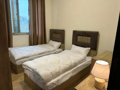 two beds in a room with a window at Luxury Abdoun apartment in Amman