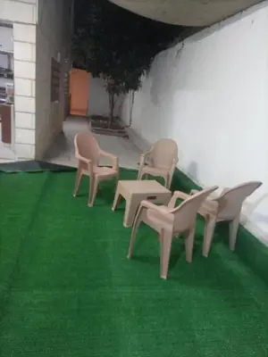 a row of chairs and a table on a green floor at Decapolis with garden in Irbid