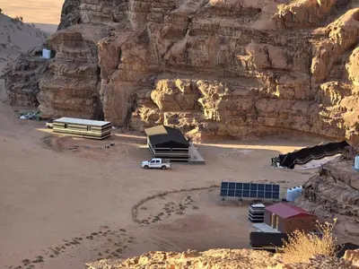 an aerial view of a desert with a mountain at Luxury tent camp in Wadi Rum