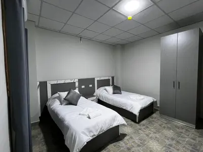 a room with two beds with white sheets at Downtown Inn Madaba in Madaba