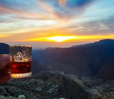 a person holding a glass of drink on top of a mountain at Dana Tower Hotel in Dana