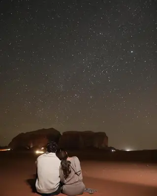 a couple sitting on the beach looking at the stars at Lucas Camp Wadi Rum in Wadi Rum