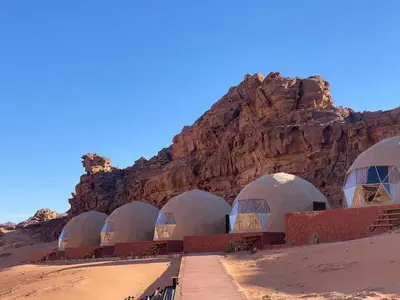 a row of domes in the desert next to a mountain at Lucas Camp Wadi Rum in Wadi Rum