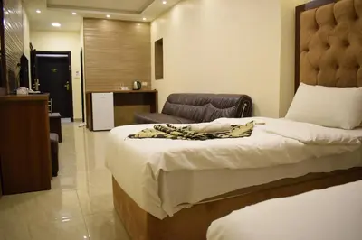 a bedroom with a large bed and a chair at Nour Hotel in Amman