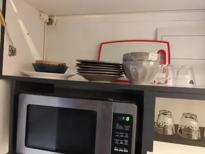 a microwave with a shelf on top of it at Gentle Breeze Studio 1 in Amman