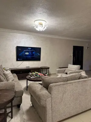 a living room with couches and a tv on a wall at Luxury Family Apartment With Balcony in Amman