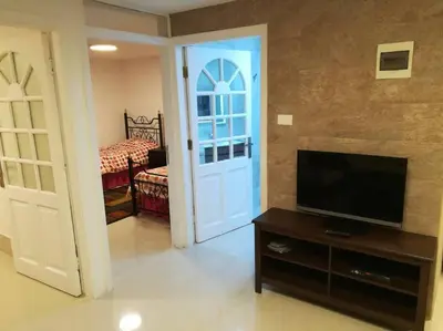 a living room with a door and a tv and a bedroom at ‘C’ DAZZLING MODERN 2 BDRM APT IN KHALDA Free WIFI in Amman
