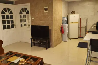 a living room with a television and a refrigerator at ‘C’ DAZZLING MODERN 2 BDRM APT IN KHALDA Free WIFI in Amman