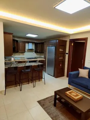 a living room with a blue couch and a kitchen at Dair Ghbar - Amman Apartment in Amman