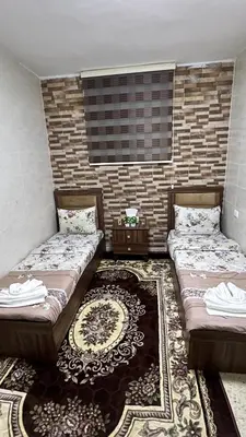 two beds sitting in a room with a rug at Blue Bird House in Wadi Musa