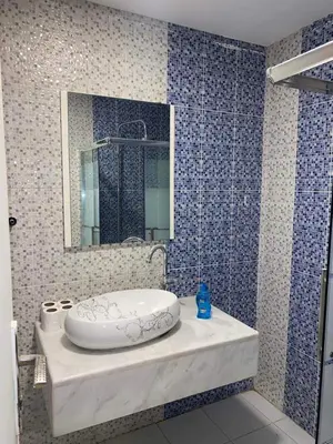 a blue tiled bathroom with a sink and a mirror at The view in Amman