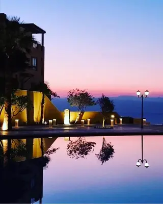 a night view of a building with a reflection in a pool at EP1 TWO BEDROOM APARTMENT AT Samarah Resort in Sowayma