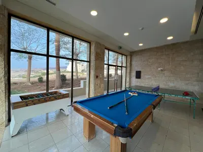 a pool table in a room with windows at EP1 TWO BEDROOM APARTMENT AT Samarah Resort in Sowayma