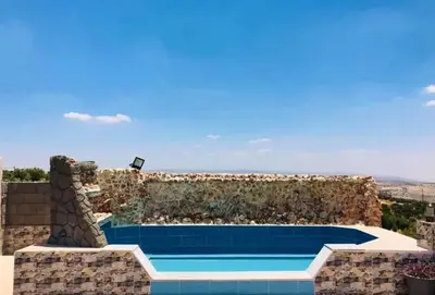 a house with a swimming pool and a stone wall at Magical Rosemary Chalet in Al Mashāriqah