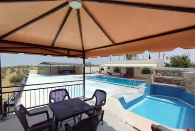 a patio with a table and chairs next to a swimming pool at Magical Rosemary Chalet in Al Mashāriqah