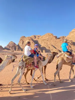 a group of people riding on camels in the desert at nature camp in Wadi Rum