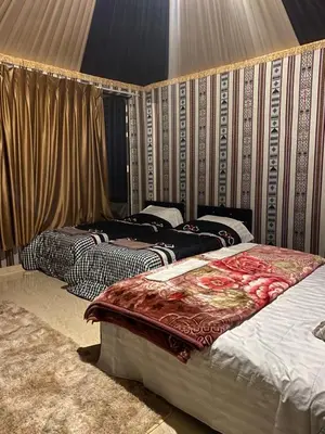 two beds sitting in a room with curtains at nature camp in Wadi Rum