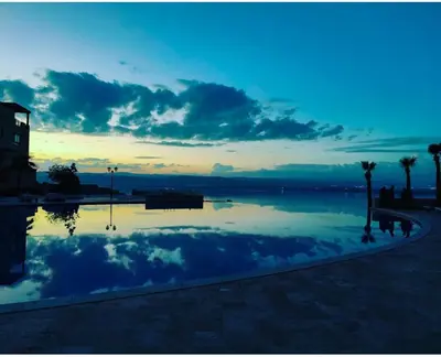 a large swimming pool with a sunset in the background at E21 Samarah Resort Apartments in Sowayma