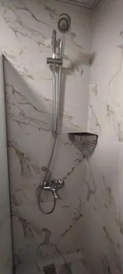 a shower in a bathroom with a marble wall at Moab Land Hotel in Madaba