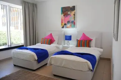 two beds in a bedroom with pink and blue pillows at Prime Hotel in Amman