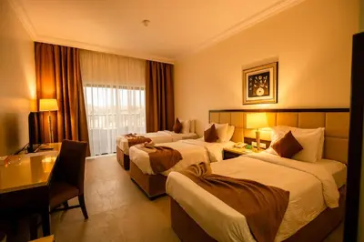 a hotel room with three beds and a desk at East hotel in Sowayma
