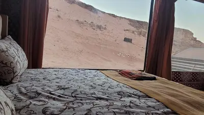 a bed in a room with a view of a desert at Rum Gonesh Luxury Camp in Wadi Rum