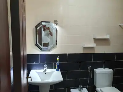 a person taking a picture of a bathroom with a sink at Noor Apartment in Amman