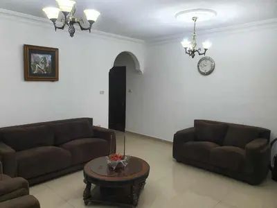 a living room with two couches and a clock on the wall at Noor Apartment in Amman