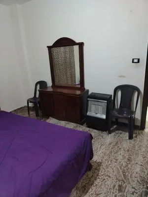 a bedroom with a bed and a dresser and chairs at الشقة العائلية الحديثة familial new flat in Amman